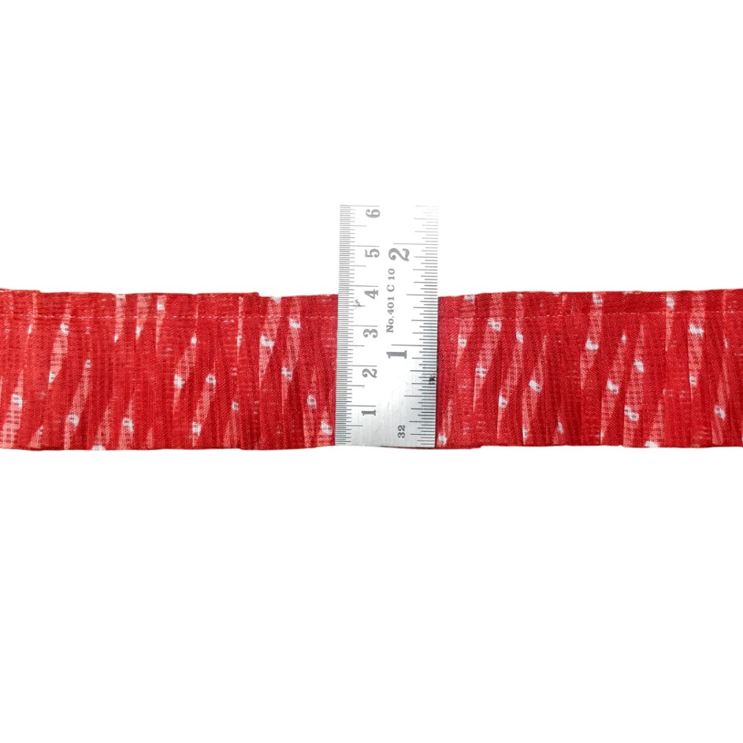 Red ribbon with a white pattern and a ruler for scale on a white background