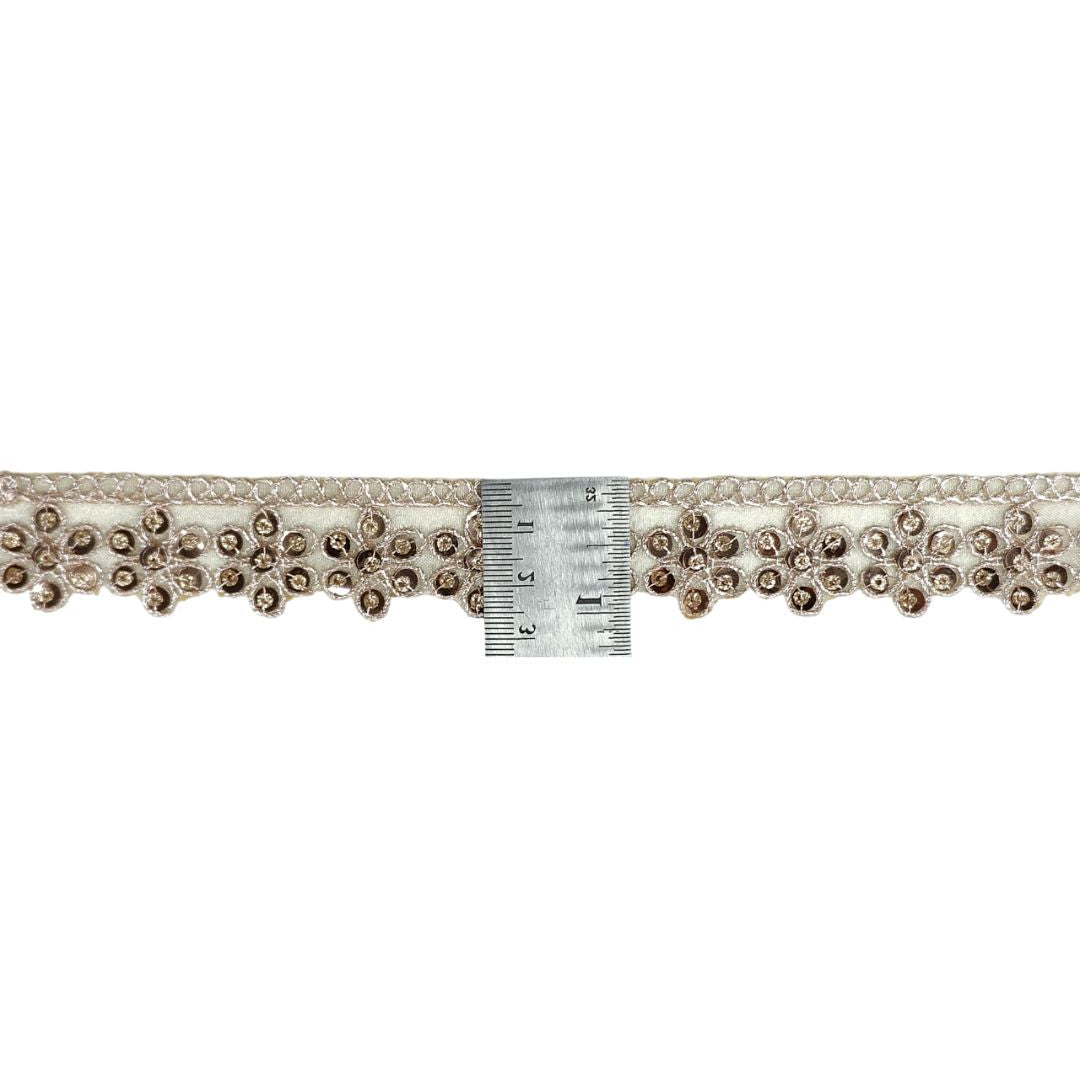 Decorative lace trim with beads and a ruler for scale on a white background