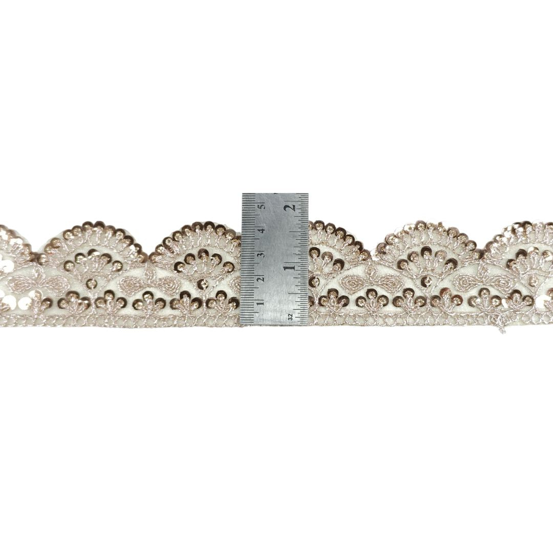 Decorative lace trim with a ruler for scale on a white background