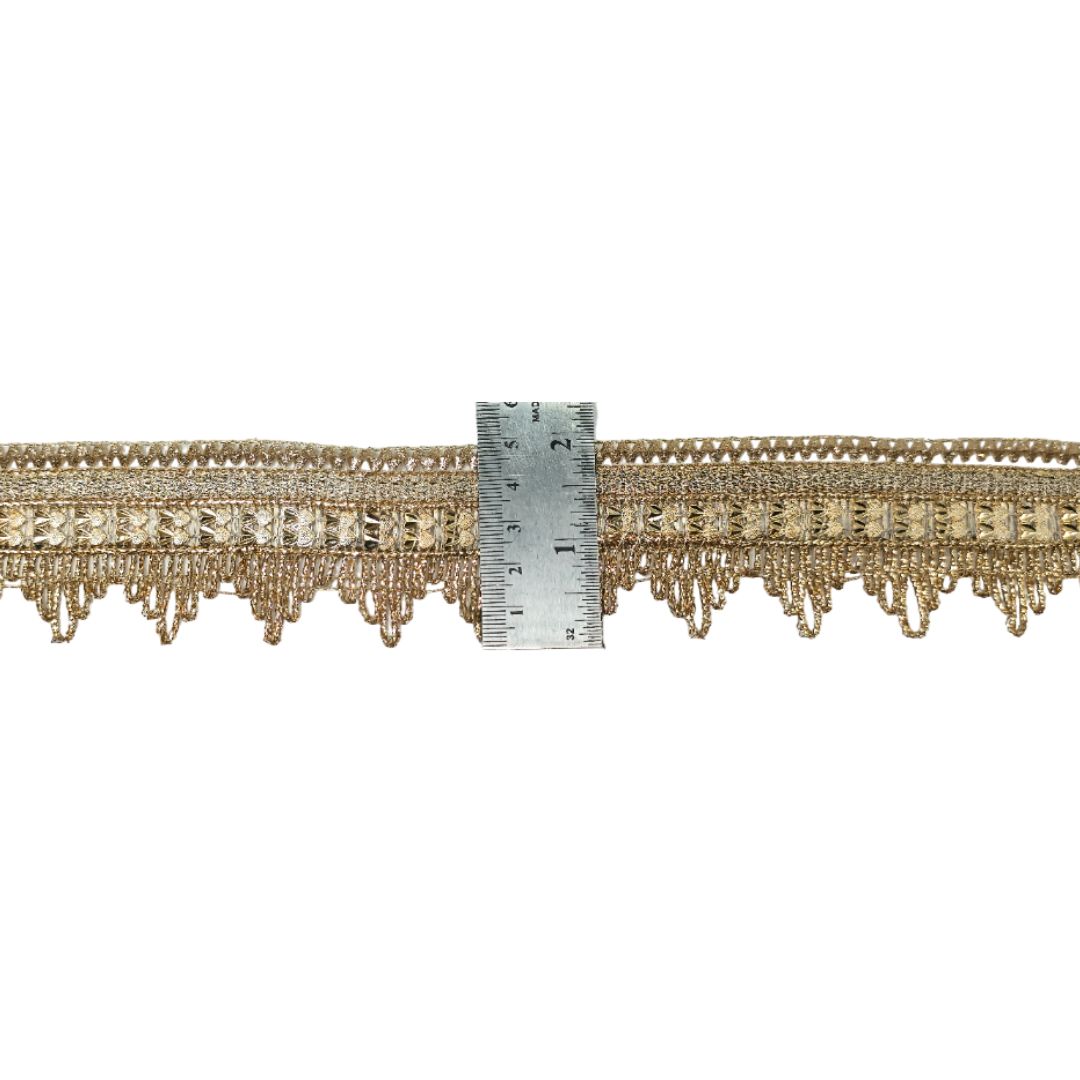Decorative gold fringe trim with a ruler for scale on a white background