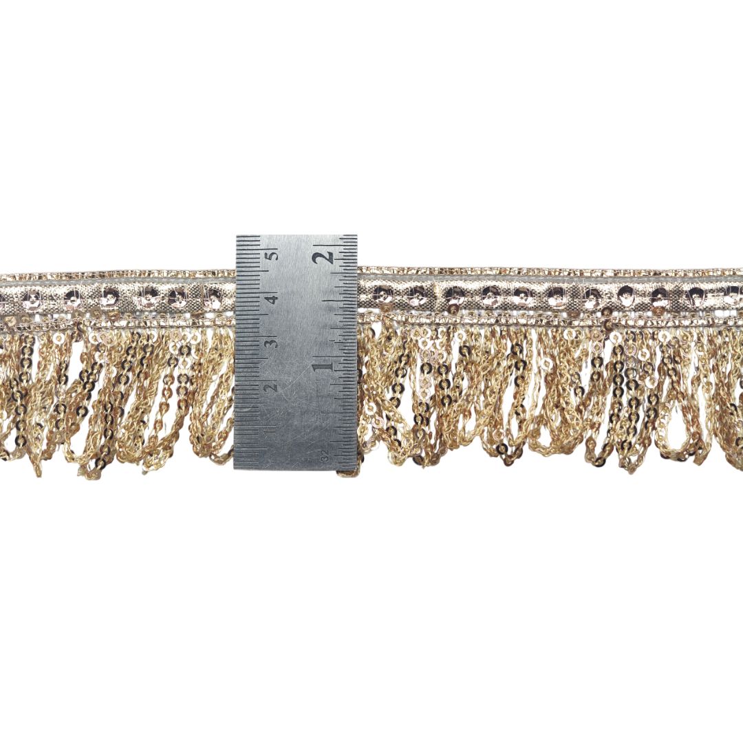 Gold fringe trim with a ruler for scale on a white background