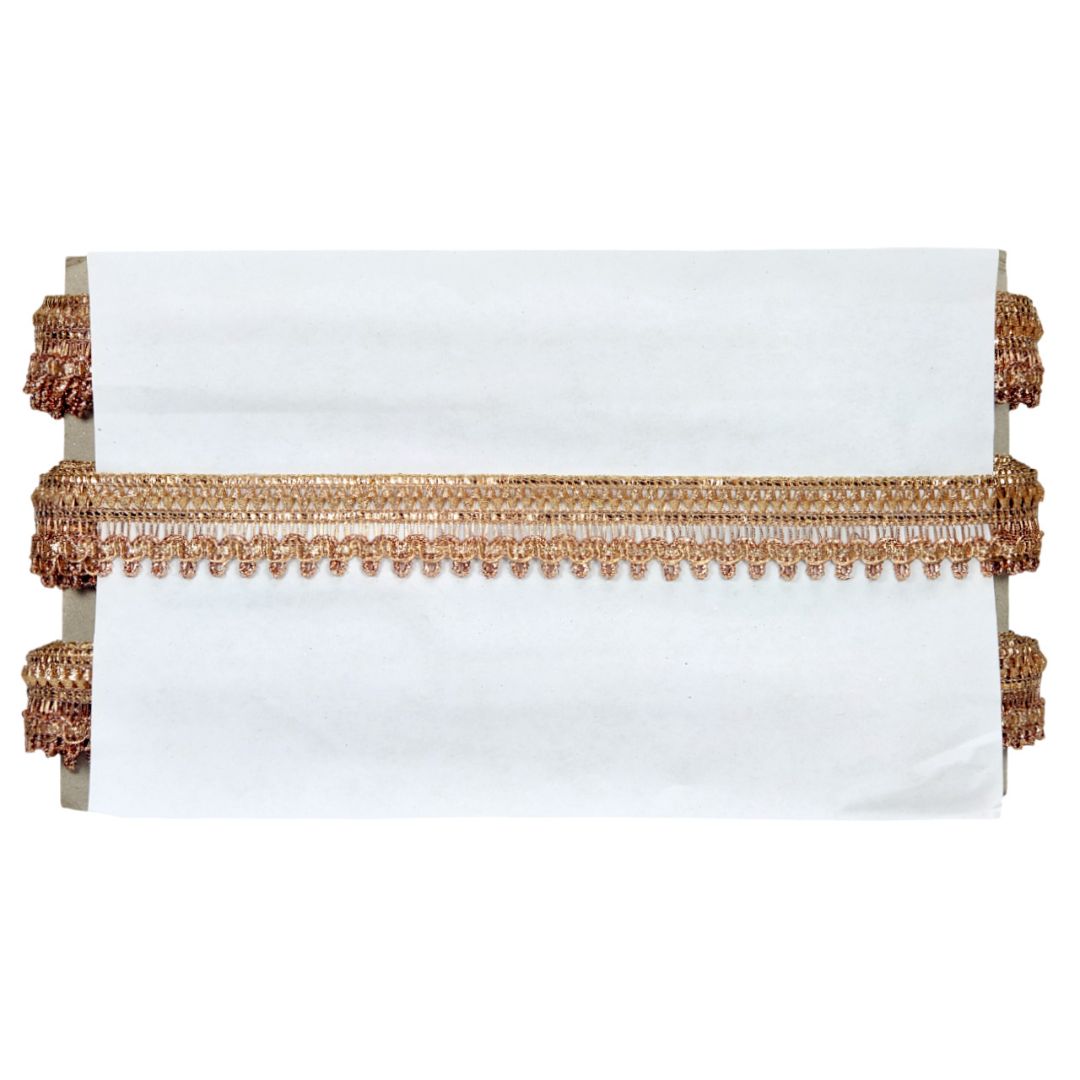 White pillow with gold fringe on a white background