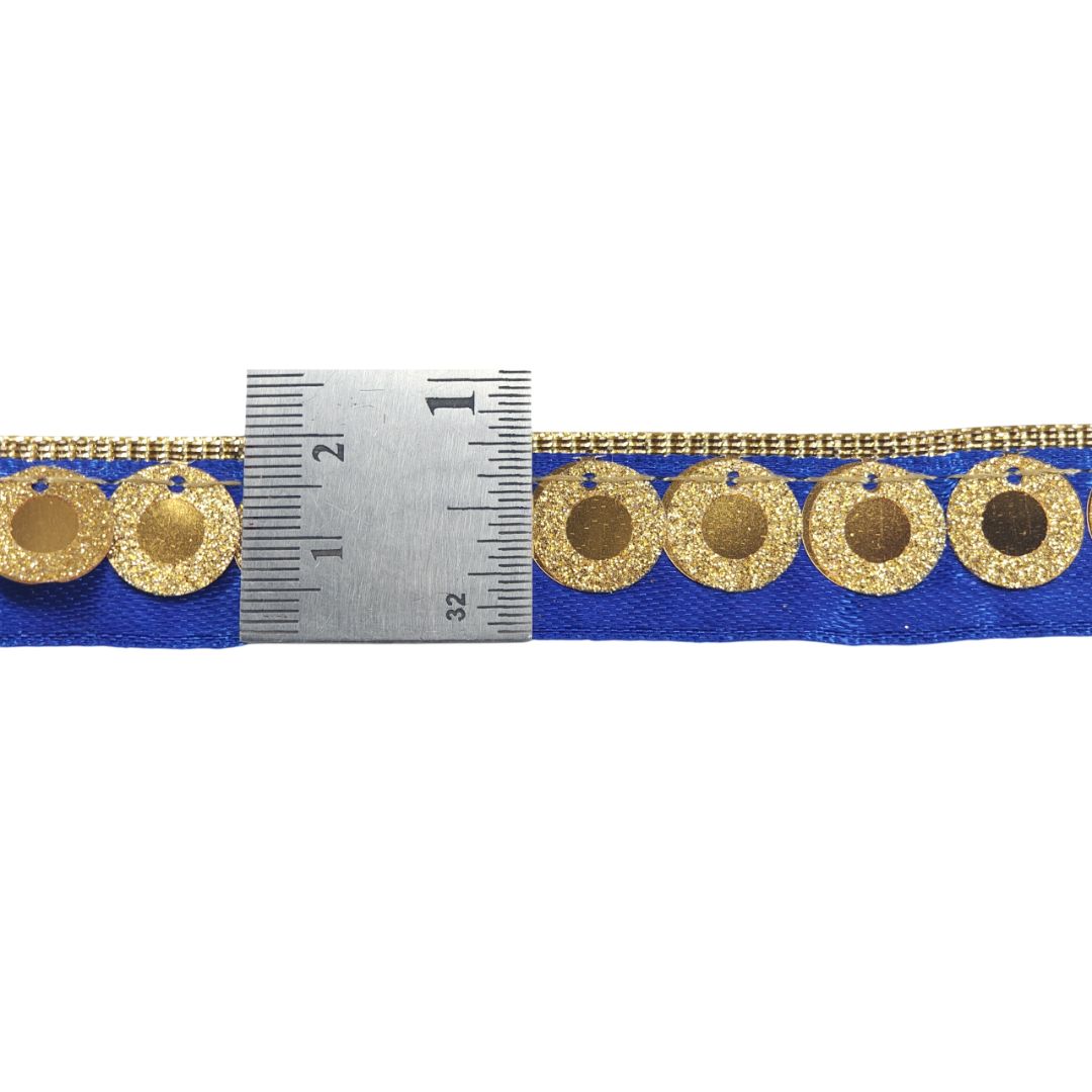 Blue ribbon with gold circular patterns and a ruler for scale on a white background