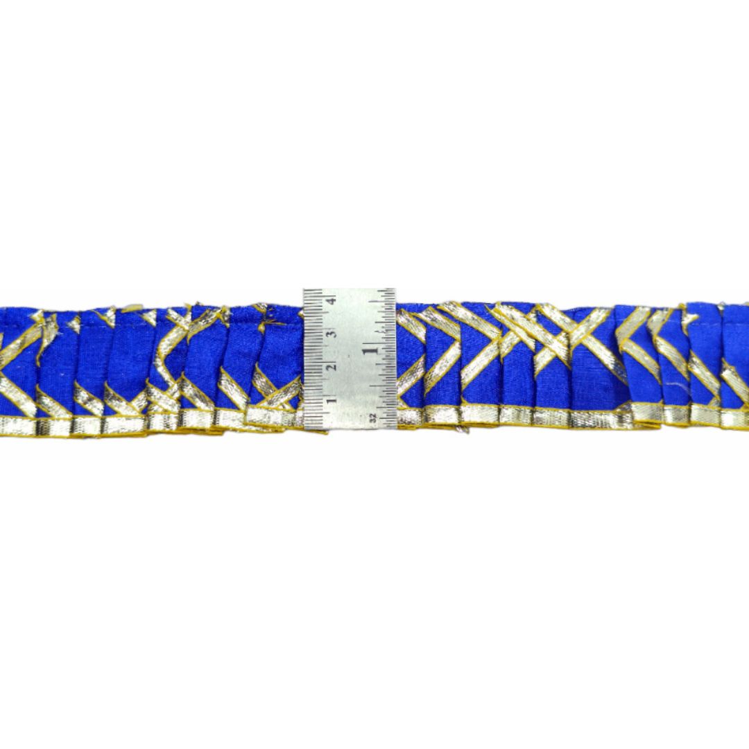 Blue ribbon with gold patterns and a ruler for scale on a white background