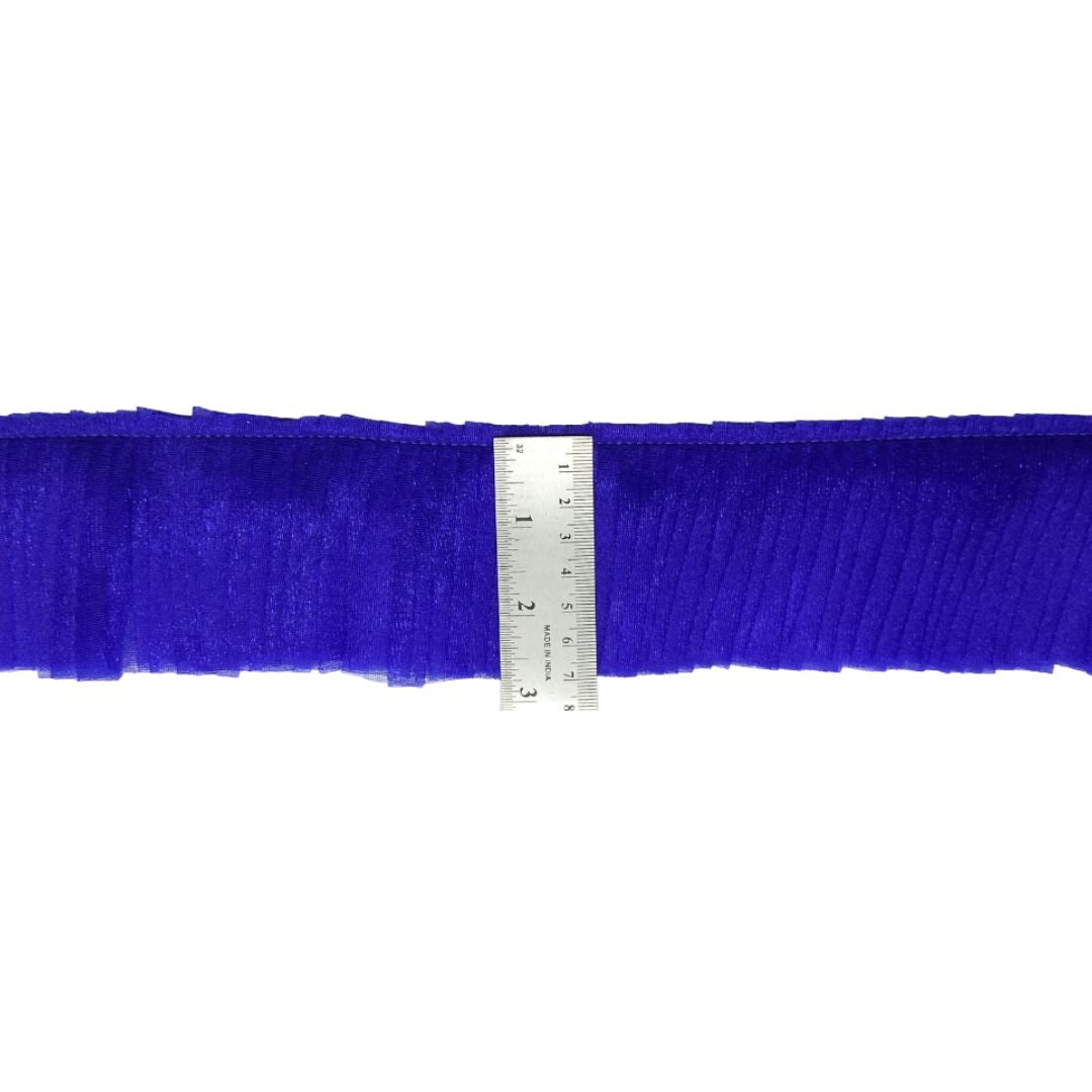 Blue ruffled trim with a ruler for scale on a white background