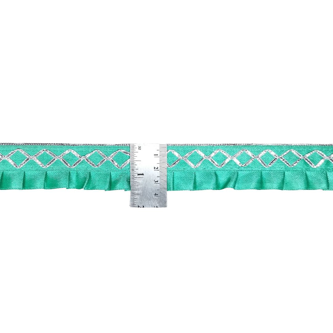Teal ribbon with white pattern and a ruler for scale on a white background