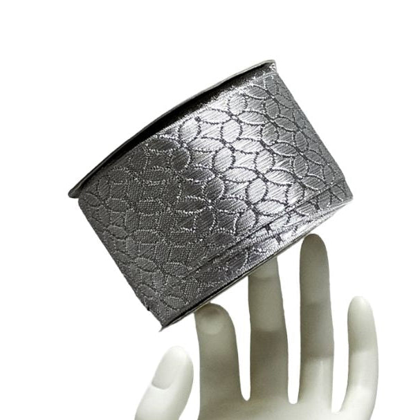 Silver textured container on a white mannequin hand against a white background