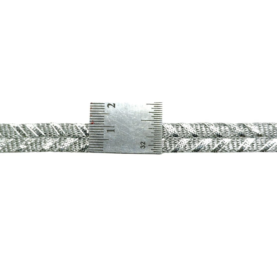 Close-up of braided silver cord with a ruler for scale on a white background