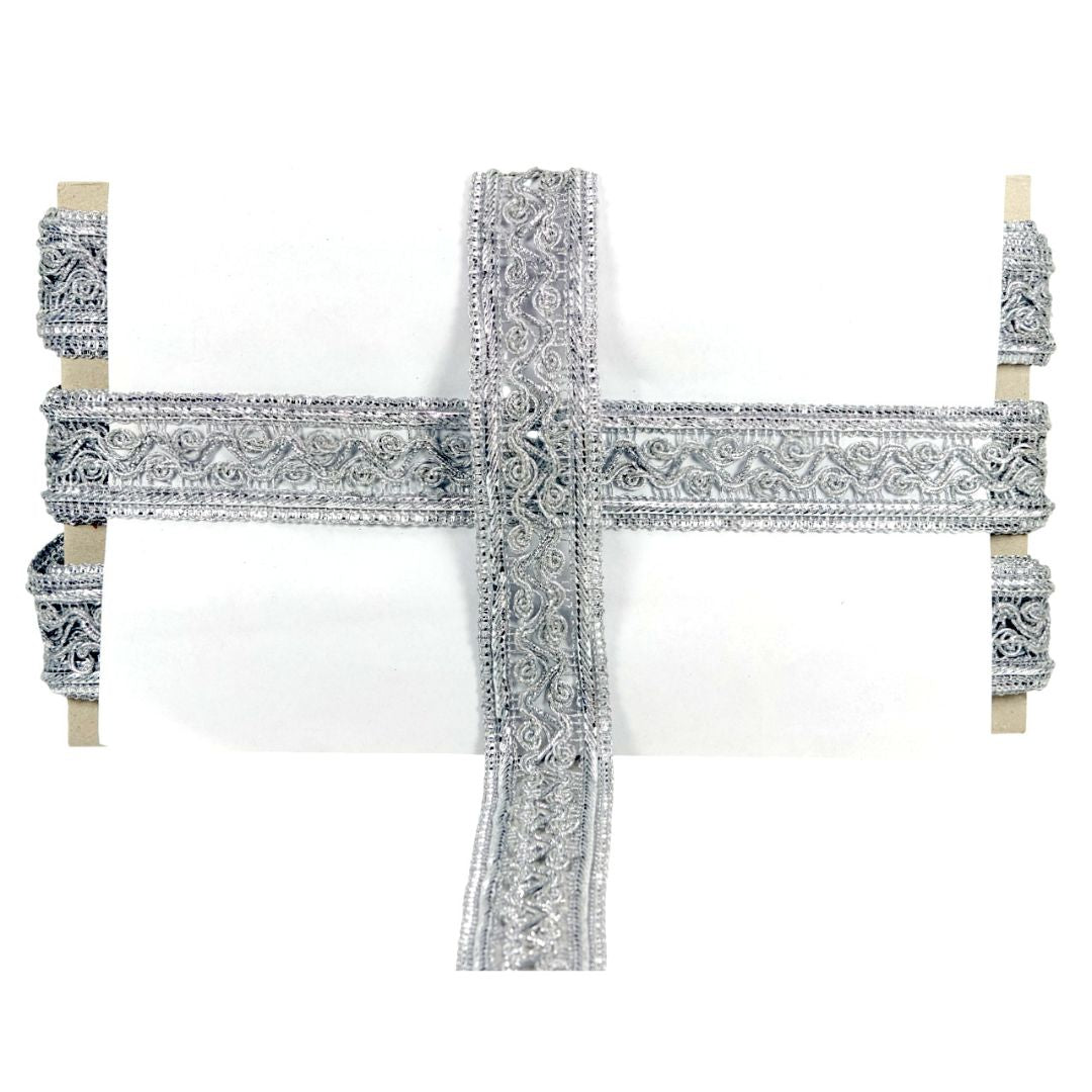 Decorative cross with intricate silver design on a white background