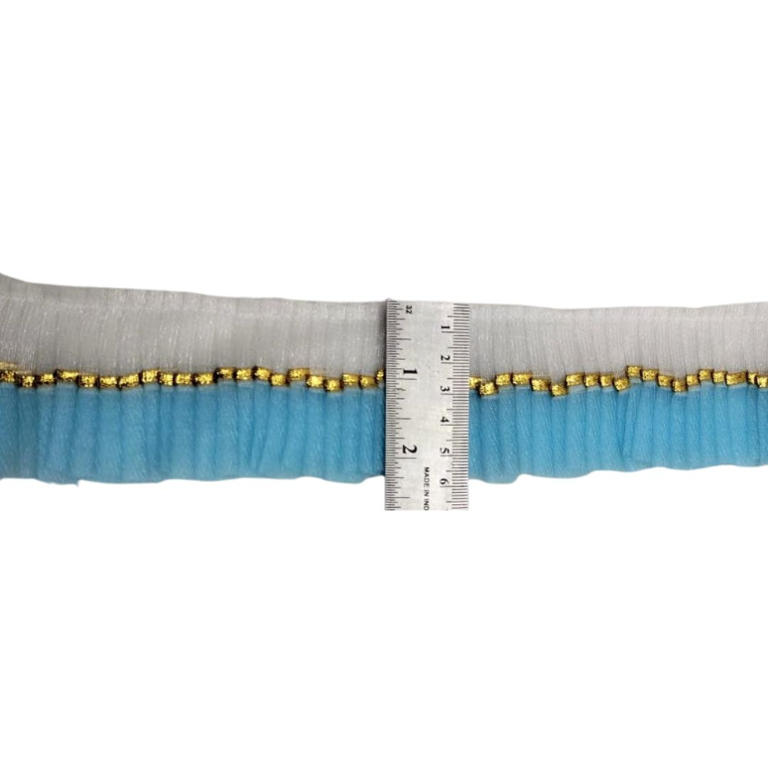 Strip of fabric with gold beads and a ruler for measurement on a white background