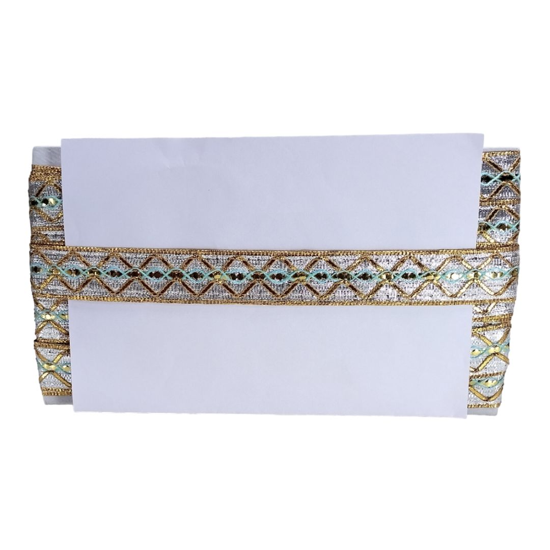 White clutch bag with gold and green decorative trim on a white background