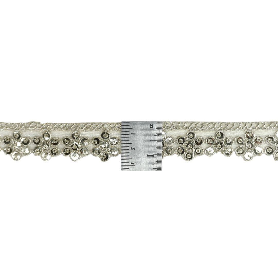 Decorative lace trim with crystals and a ruler for scale on a white background