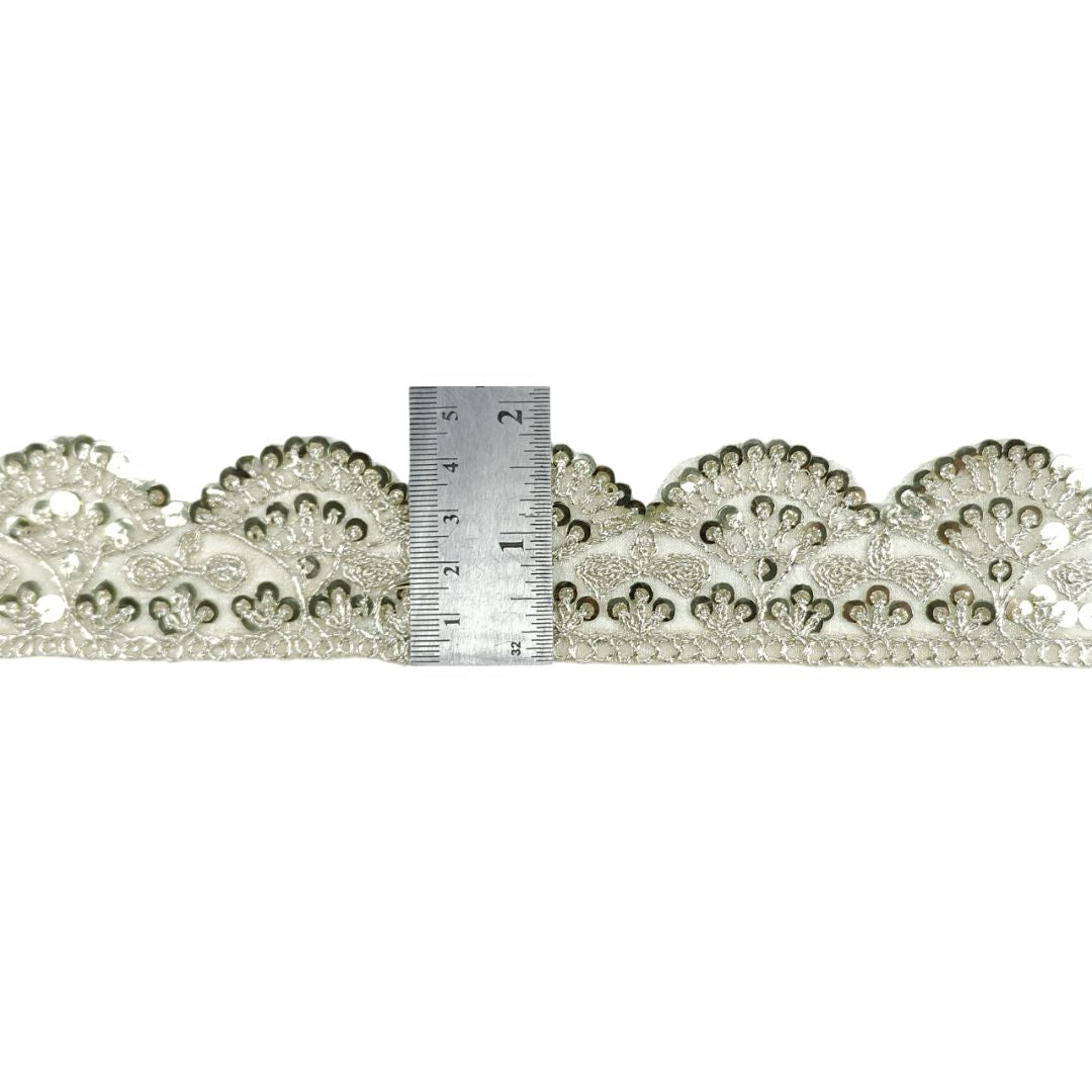 Decorative lace trim with a ruler for scale on a white background