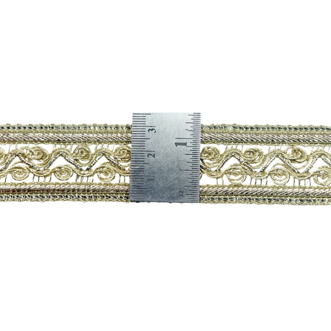 Decorative gold lace trim with a ruler for measurement on a white background