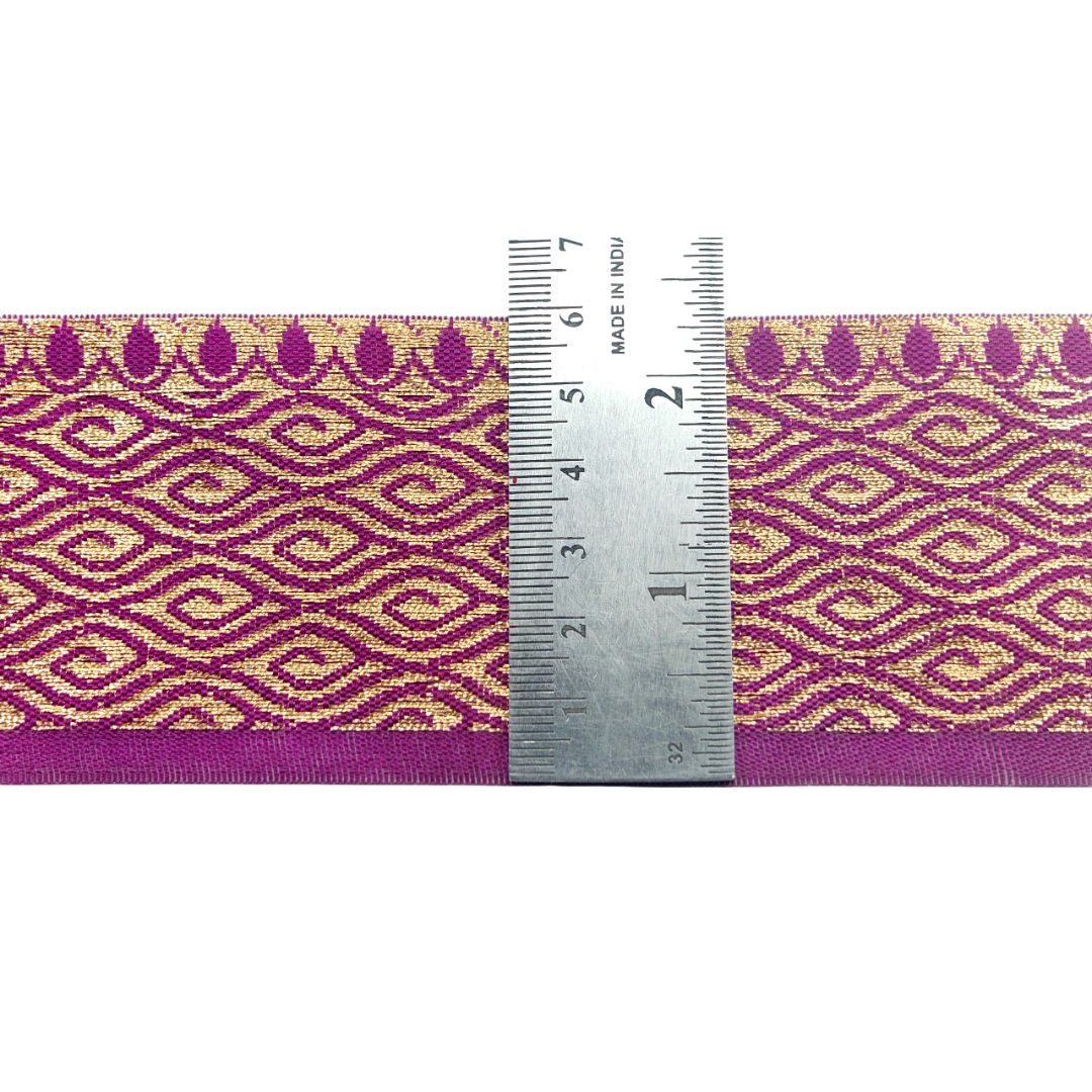 Purple and gold patterned ribbon with a ruler for scale on a white background