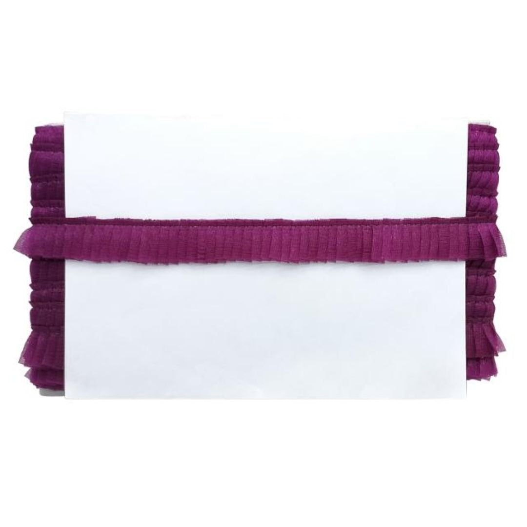 White pillow with purple ruffled trim on a white background