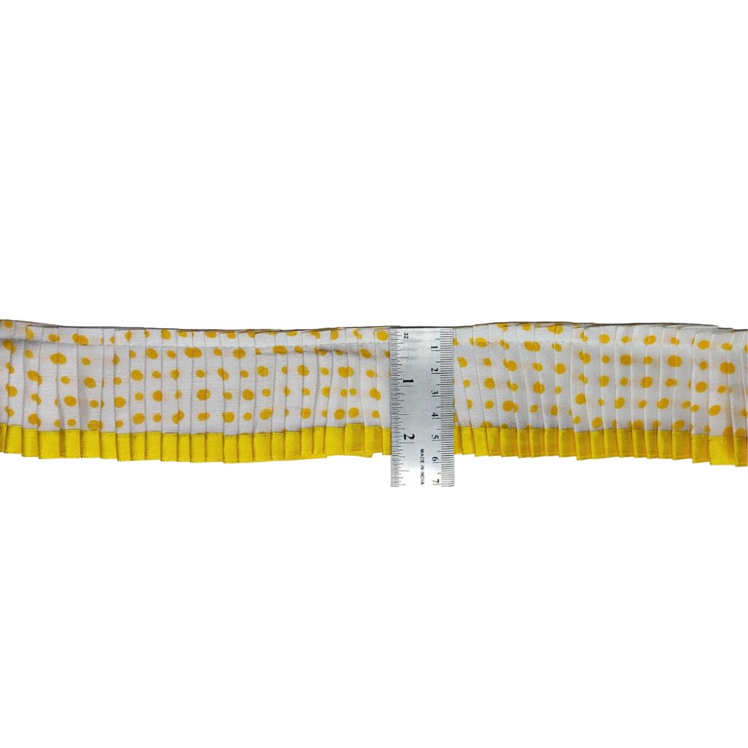 Strip of fabric with yellow polka dots and a yellow border, measured against a ruler on a white background.
