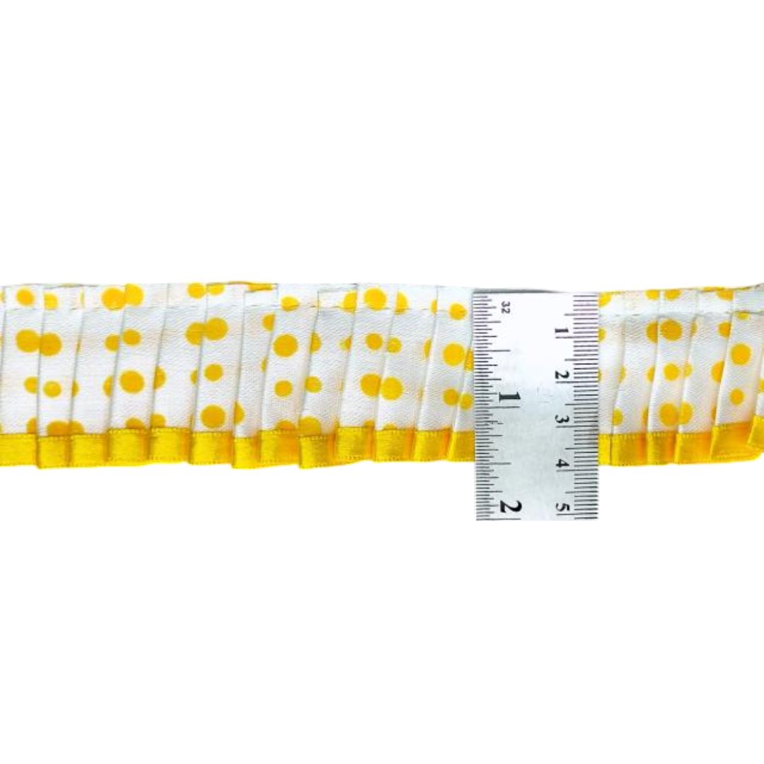 Yellow and white polka dot ribbon with a ruler for measurement on a white background