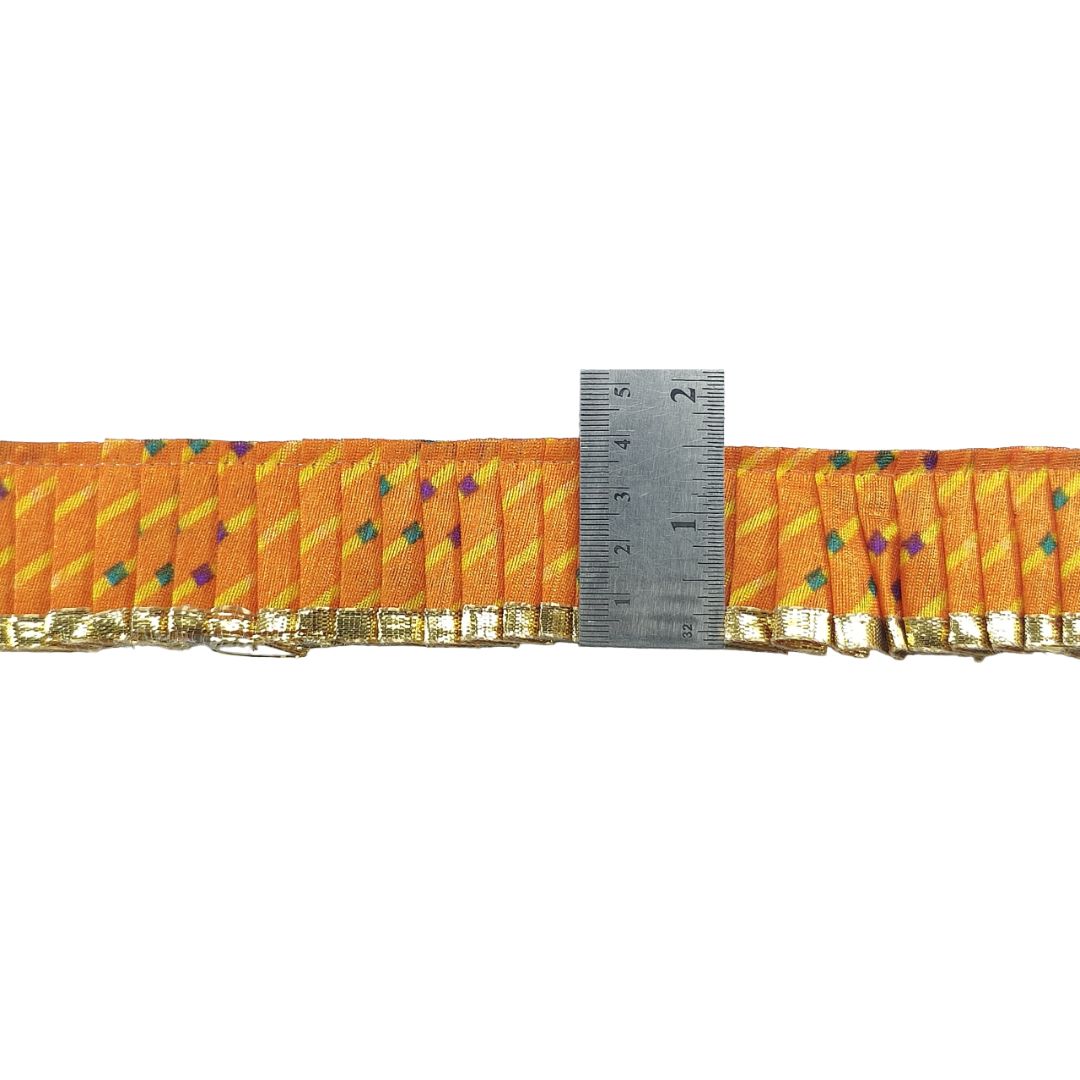 Orange ribbon with gold trim and colorful polka dots, measured against a ruler on a white background.