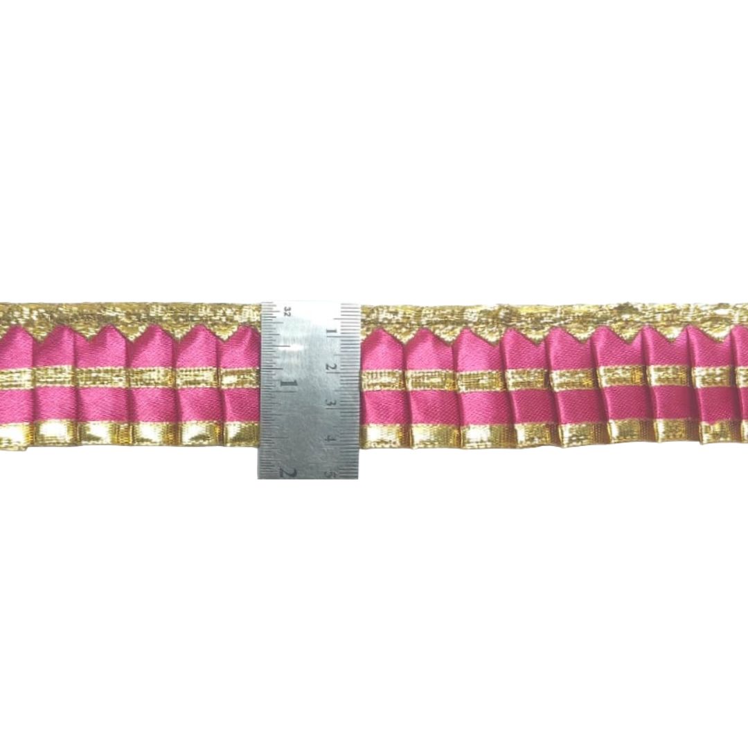 Pink and gold striped fabric with a ruler for scale on a white background