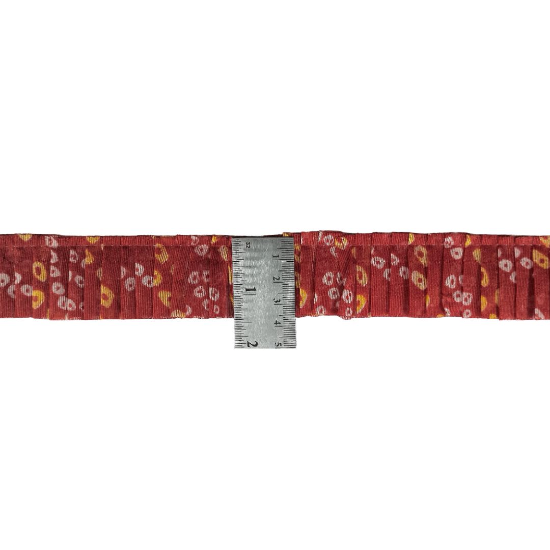 Red floral-patterned belt with a measuring tape indicating its width on a white background